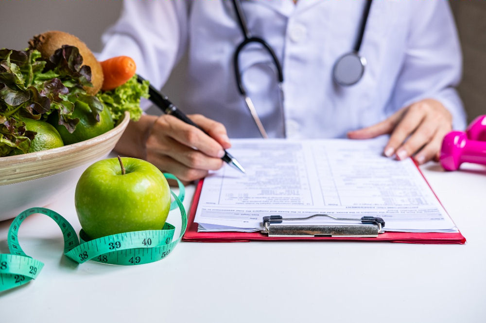 Nutritionist writing on a medical form, discussing how poor eating habits can affect mental health and contribute to depression.